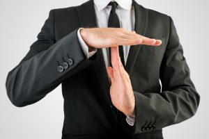 Close up Businessman in Black Suit Showing Time Out Sign, Isolated on Gray Background.